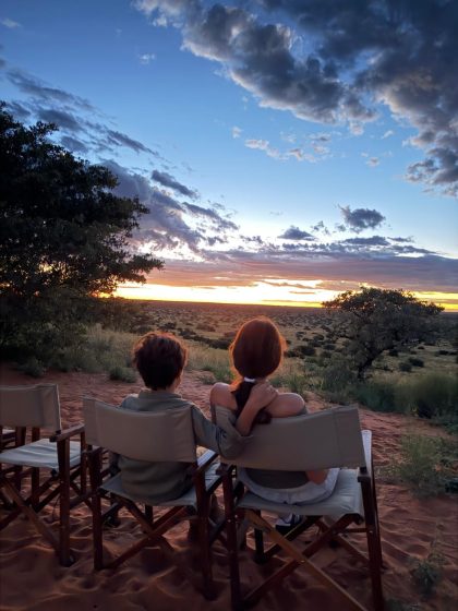 A mother and child watching the sun set over the Kalahari